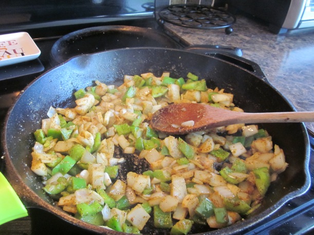 skillet with onions and green bell peppers for white enchiladas
